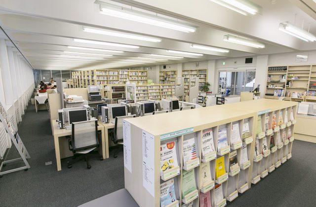 書籍が詰まった本棚とパソコンが整然と並べられた図書館の写真