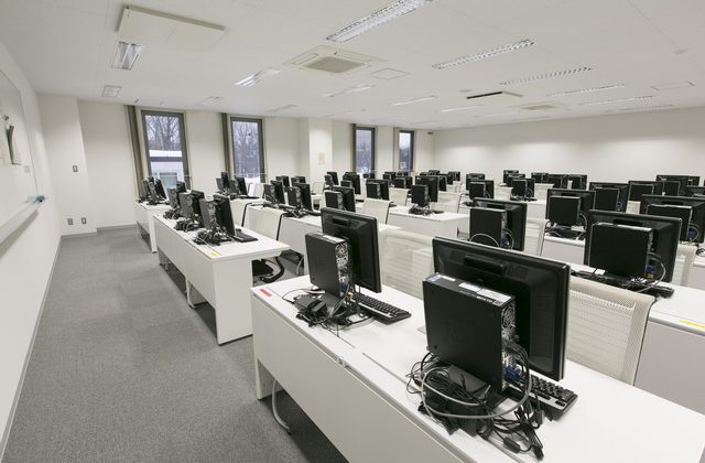 パソコンが並んだ白を基調とした清潔感のあるコンピューター室2の写真
