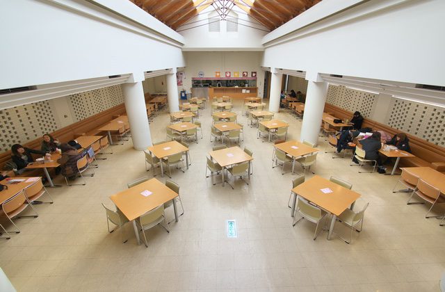 4人掛けの机と椅子が多く配置された開放感のある学生ホールの写真