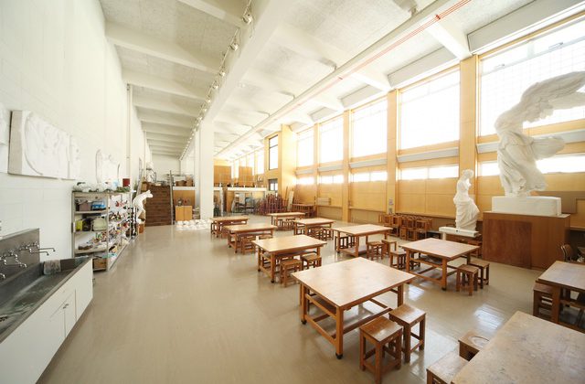 理路整然と木材机が並ぶ横にサモトラケのニケなどの石膏のレプリカが置かれているデザイン実習室の写真